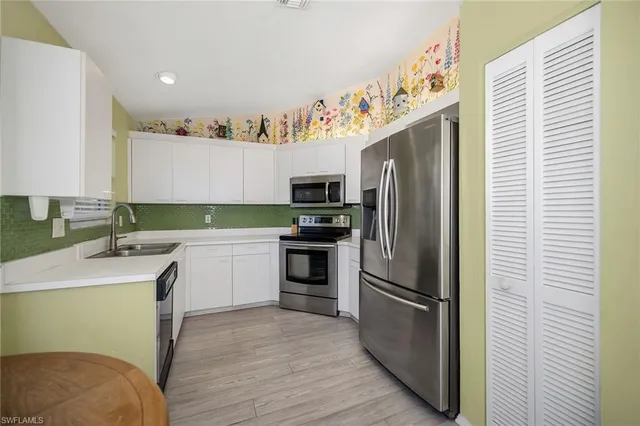 a kitchen with a sink stainless steel appliances and white cabinets