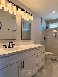 a bathroom with a granite countertop sink toilet and mirror