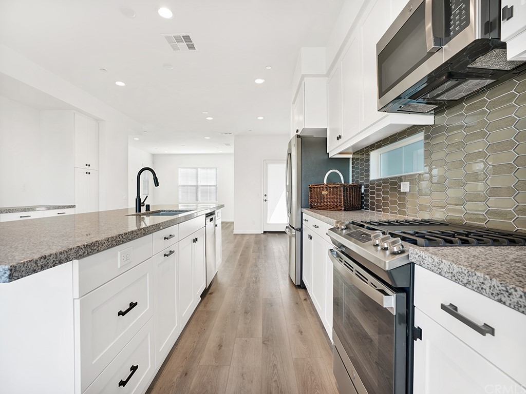 524 Caleigh Lane Costa Mesa, CA 92627 - Photo 3 of 19 a large kitchen with stainless steel appliances granite countertop a lot of counter space a sink and a stove