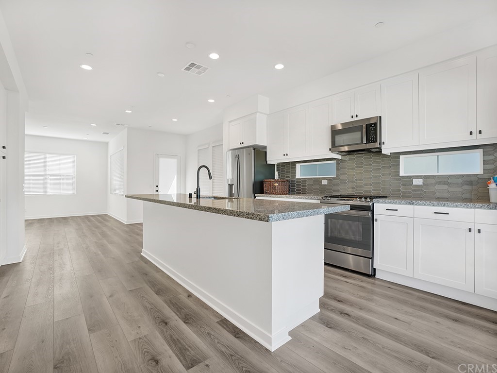 524 Caleigh Lane Costa Mesa, CA 92627 - Photo 6 of 19 a kitchen with stainless steel appliances granite countertop a stove top oven a sink and white cabinets
