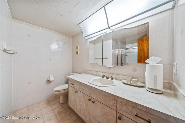 a bathroom with a granite countertop sink mirror vanity and toilet