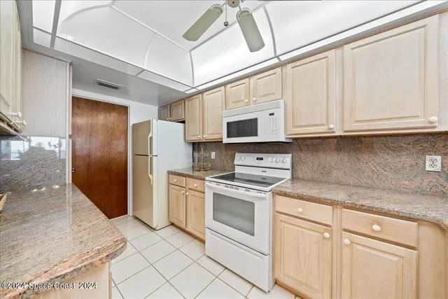 a kitchen with stainless steel appliances granite countertop a refrigerator a stove and white cabinets with wooden floor