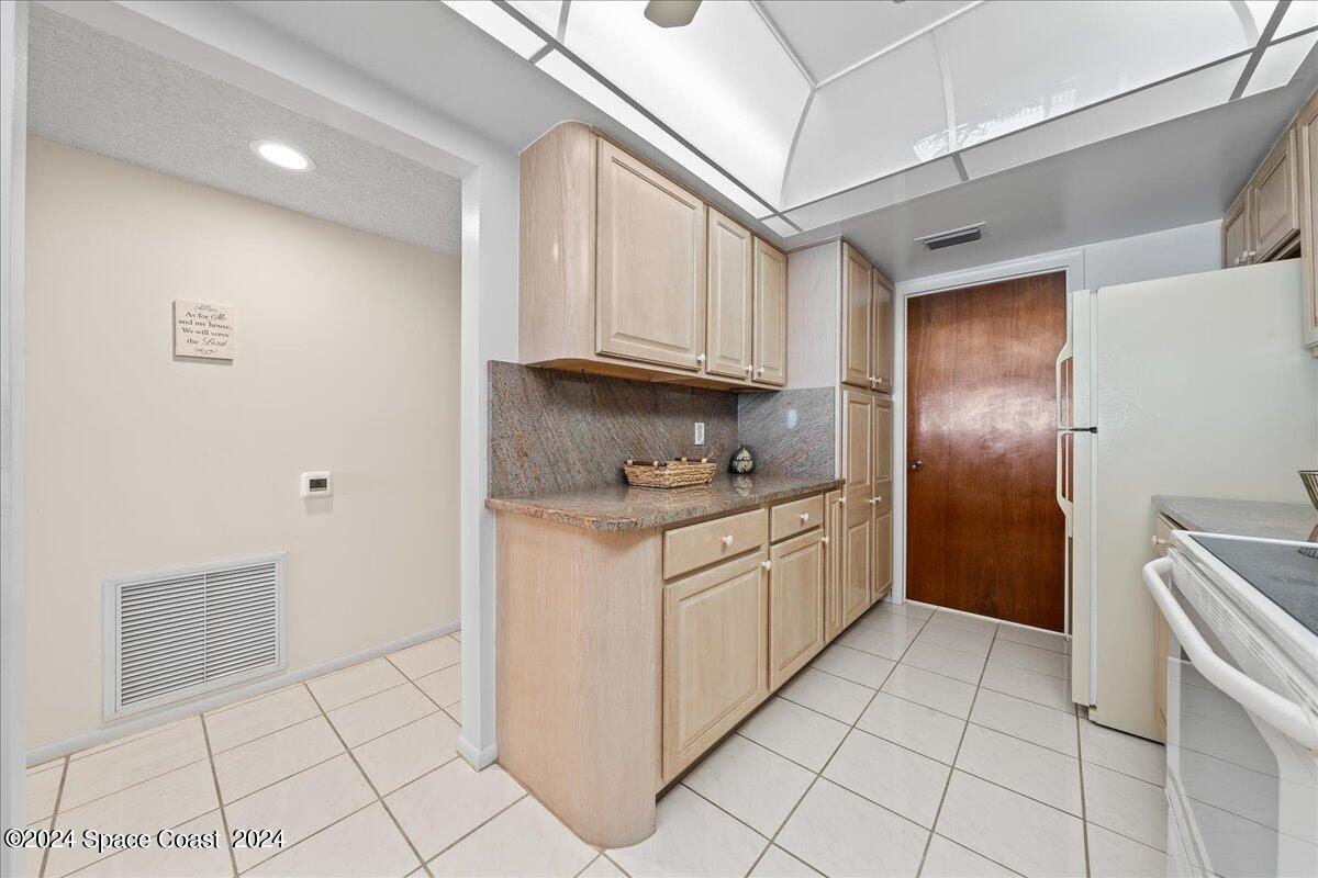 2725 North Hwy A1A, Unit 403 Indialantic, FL 32903 - Photo 8 of 37 a kitchen with granite countertop white cabinets and stainless steel appliances
