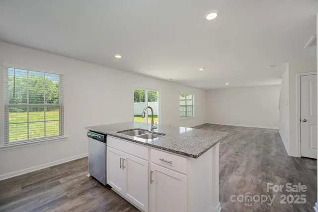 a kitchen with granite countertop white cabinets and a window