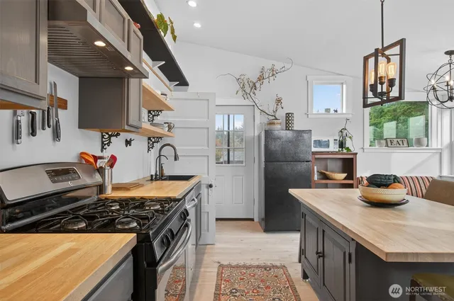 a kitchen with stainless steel appliances kitchen island granite countertop a table chairs in it and wooden floors