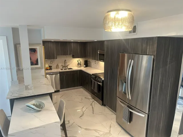 a kitchen with stainless steel appliances granite countertop a refrigerator a sink a stove and a refrigerator