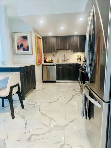 a kitchen with stainless steel appliances kitchen island granite countertop a refrigerator a stove a sink a microwave and chairs