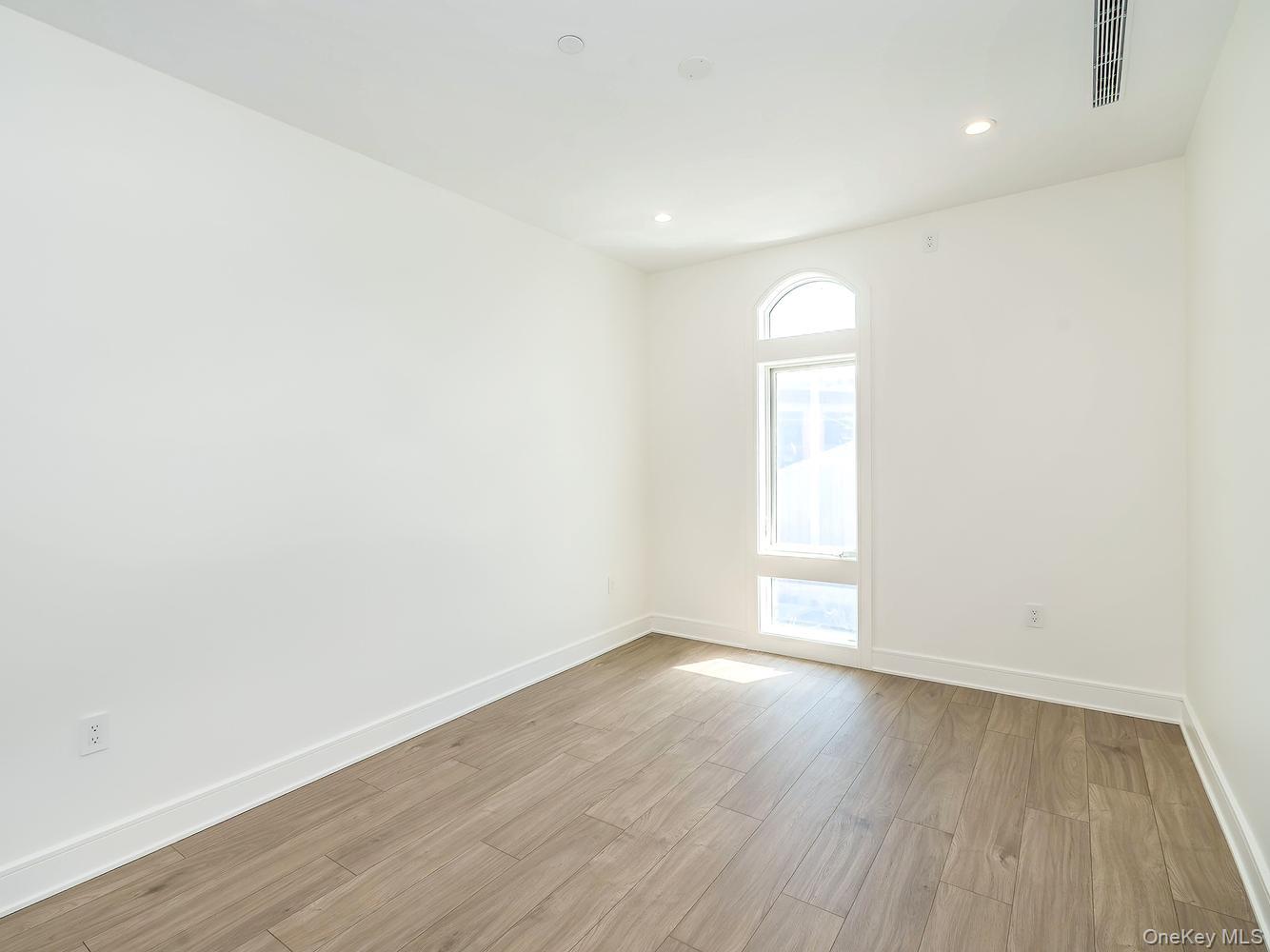 24 Lumber Road, Unit 2 Roslyn, NY 11576 - Photo 22 of 25 an empty room with wooden floor and window
