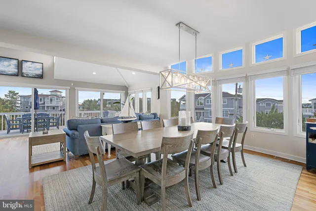 a view of a dining room and livingroom with furniture wooden floor a chandelier
