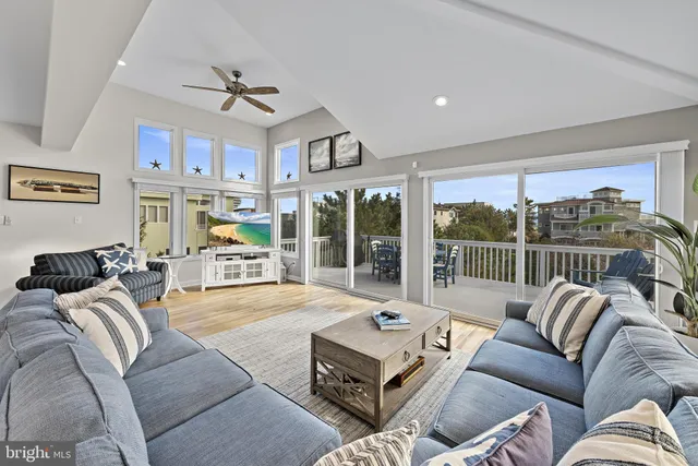 a living room with furniture large windows and a chandelier