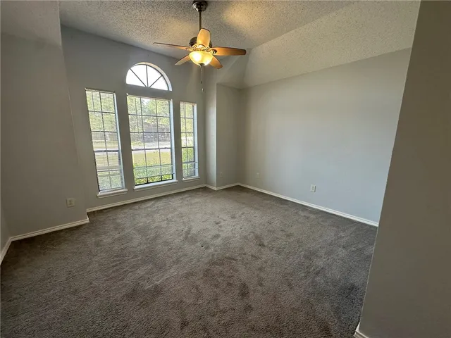an empty room with a chandelier fan and a ceiling fan