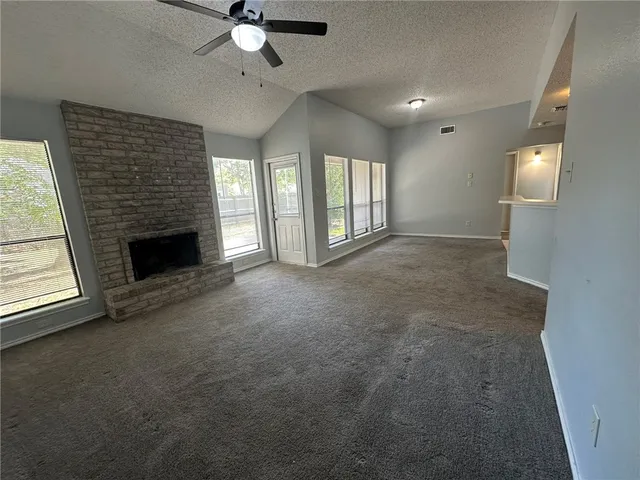 a view of an empty room with a fireplace and a window