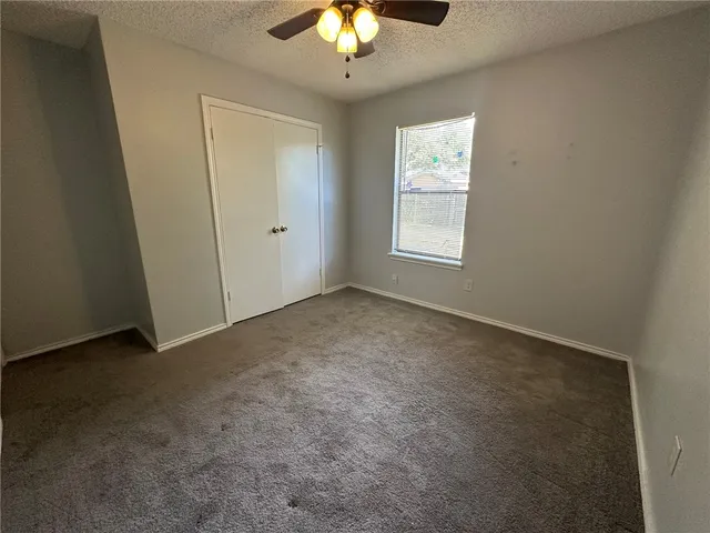an empty room with a ceiling fan and carpet