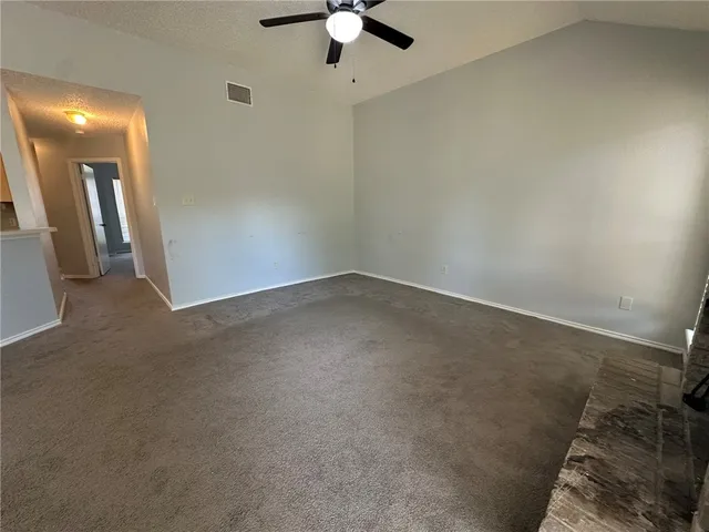 an empty room with a ceiling fan and carpet
