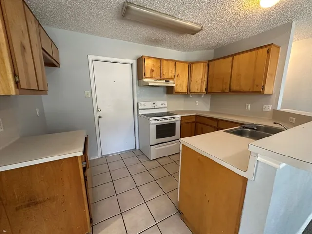 a kitchen with a sink a stove top oven and cabinetry