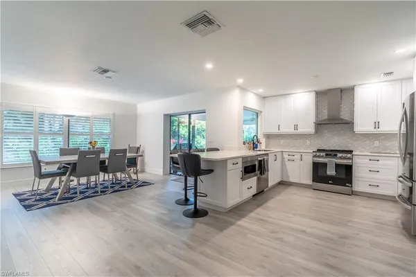 a large white kitchen with stainless steel appliances granite countertop a stove and a wooden floors