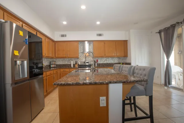 a kitchen with stainless steel appliances granite countertop a refrigerator a stove and a sink with wooden floor