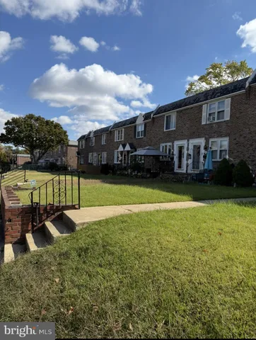 a view of a house with a yard and a large tree