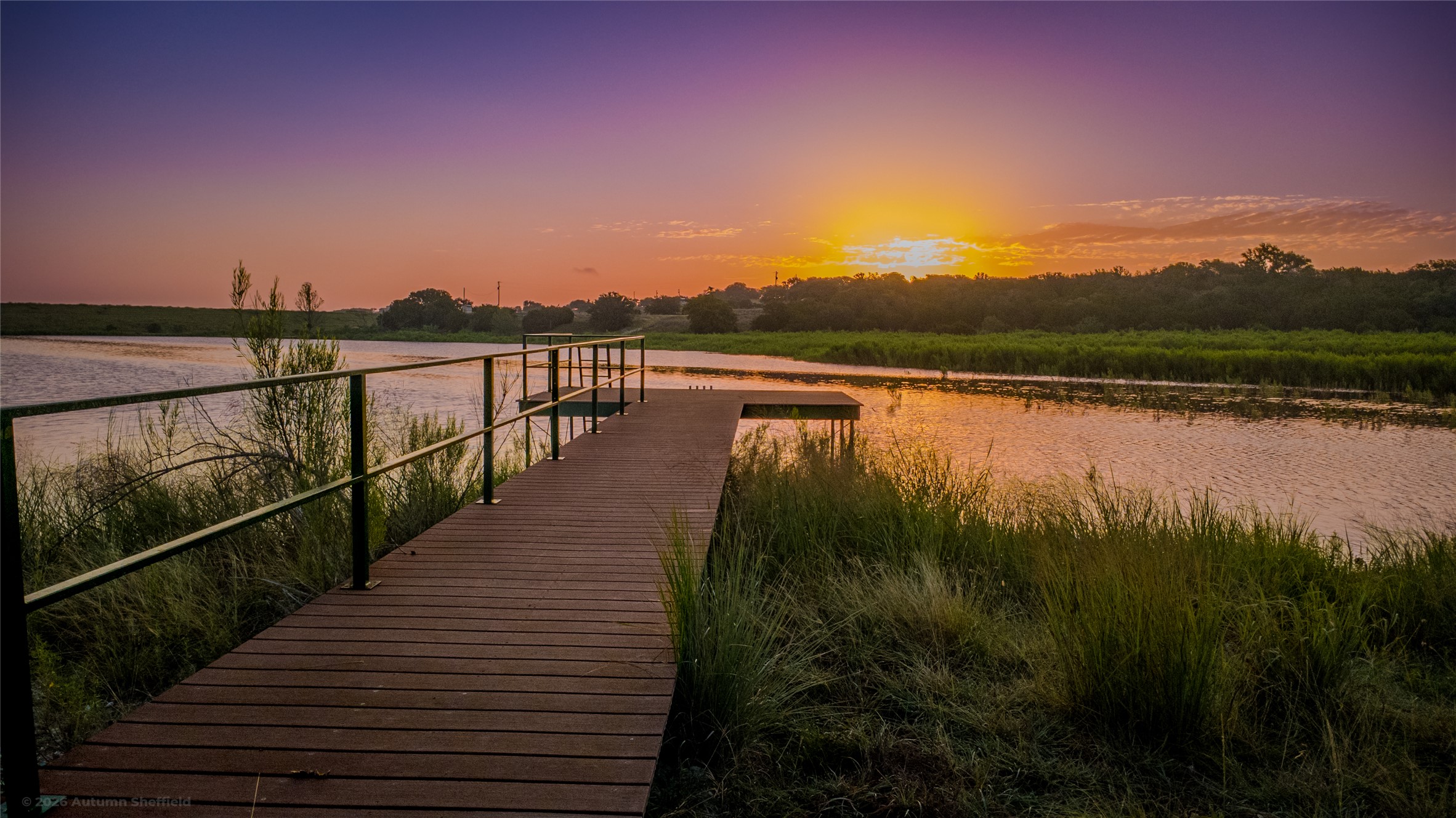 3259 Schumann Road Stonewall, TX 78671 - Photo 6 of 36 A private pier extends over the serene lake, bathed in the soft glow of sunset.