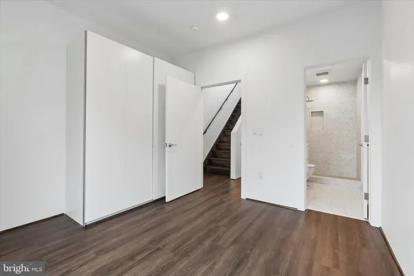 a view of an empty room with wooden floor and stairs