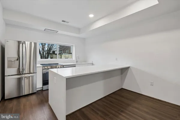 a kitchen with wooden floor and electronic appliances