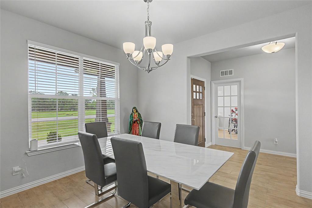 185 Chester Road Springtown, TX 76082 - Photo 11 of 40 Dining area featuring wood-finish flooring, a large window with horizontal blinds, and a contemporary chandelier