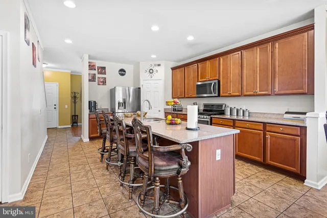 a kitchen with stainless steel appliances granite countertop a table chairs and a refrigerator