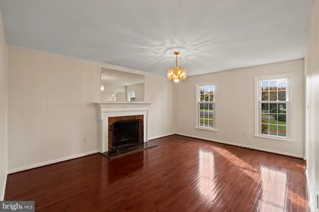 a view of an empty room with wooden floor fireplace and a window