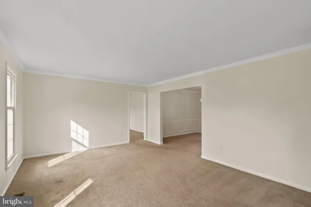 a view of an empty room with a window and a kitchen