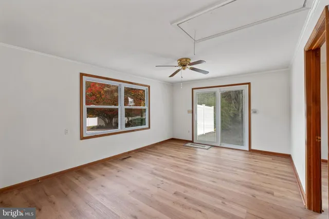 a view of an empty room with a window and wooden floor