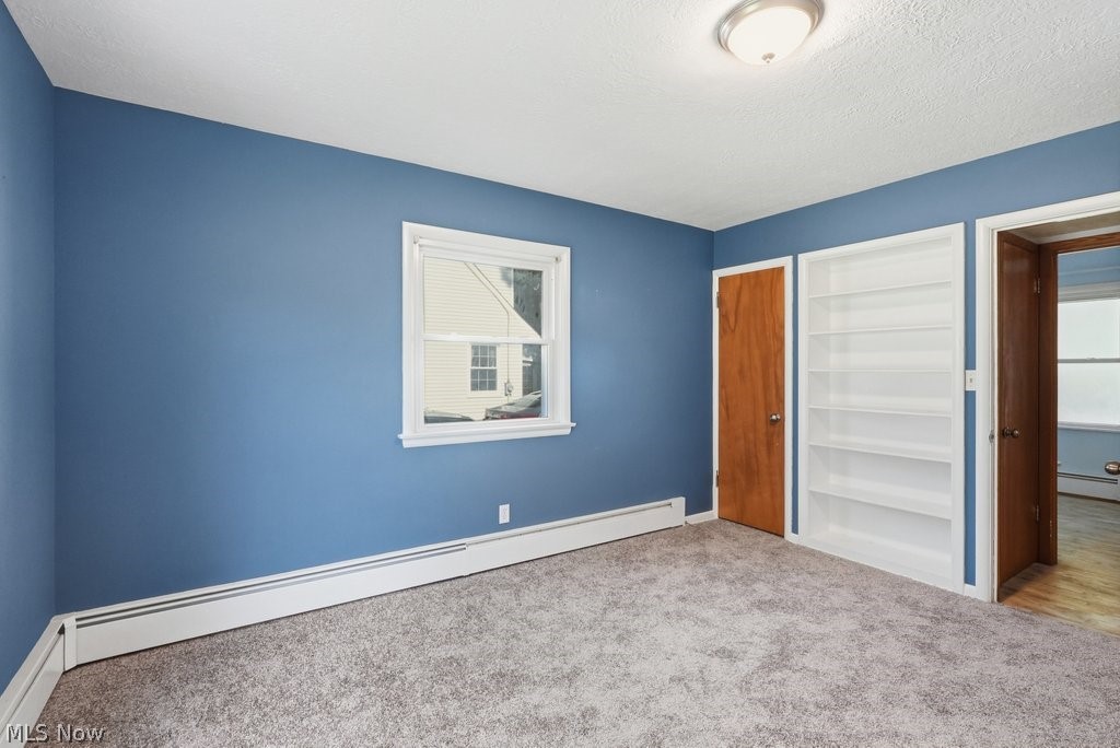 136 Pinehurst Road Munroe Falls, OH 44262 - Photo 21 of 48 Carpeted room featuring a white-trimmed window, built-in shelving, wood-finish doors, and a flush-mount ceiling light