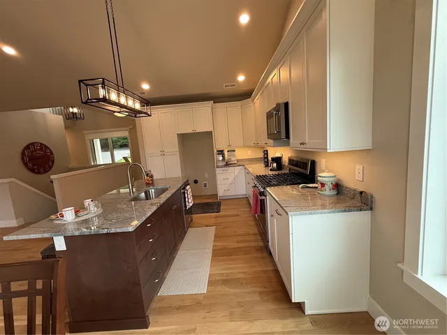 a large kitchen with kitchen island a stove a sink a refrigerator and a dining table with wooden floor