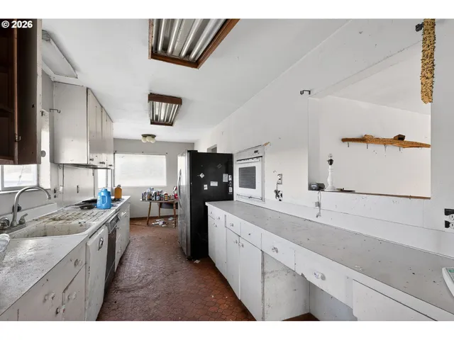 a large white kitchen with a sink and dishwasher a stove with wooden floor
