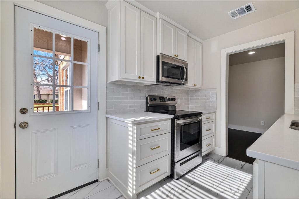 806 Denton Street Denton, TX 76201 - Photo 9 of 19 Kitchen featuring stainless steel appliances, white cabinetry, light stone countertops, light marble finish floors, and tasteful backsplash