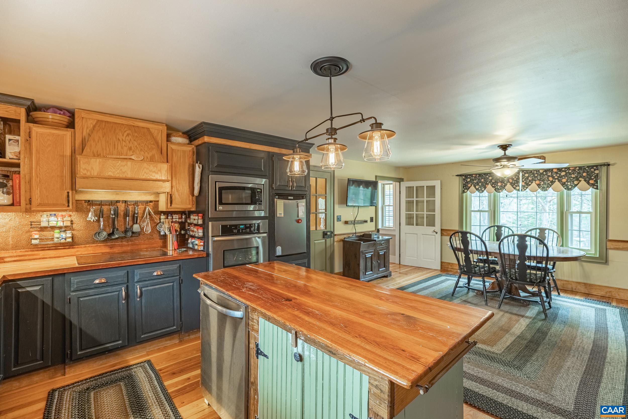 3100 Bacon School Road Saxe, VA 23967 - Photo 18 of 47 a kitchen with stainless steel appliances granite countertop a stove top oven a sink dishwasher a dining table and chairs with wooden floor