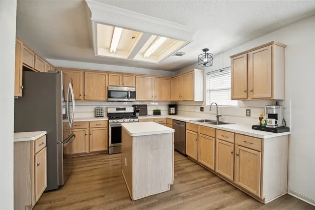 a kitchen with cabinets stainless steel appliances a sink and a window