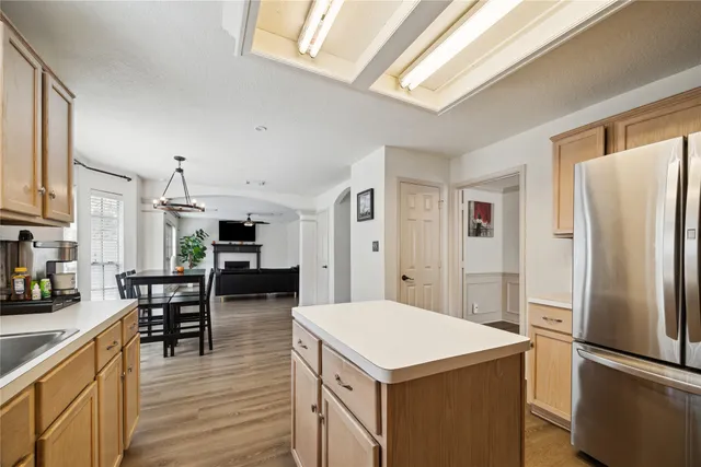 a kitchen with a refrigerator a stove top oven a sink dishwasher and a dining table with wooden floor