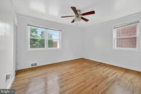 a view of empty room with wooden floor and fan