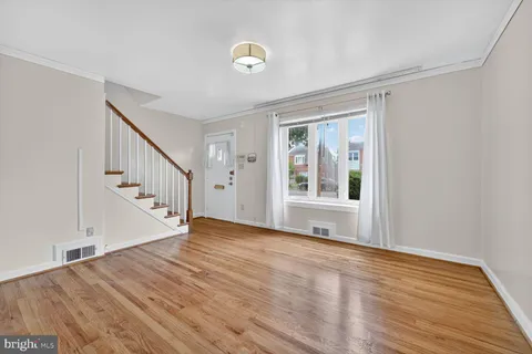 a view of an empty room with wooden floor and fan