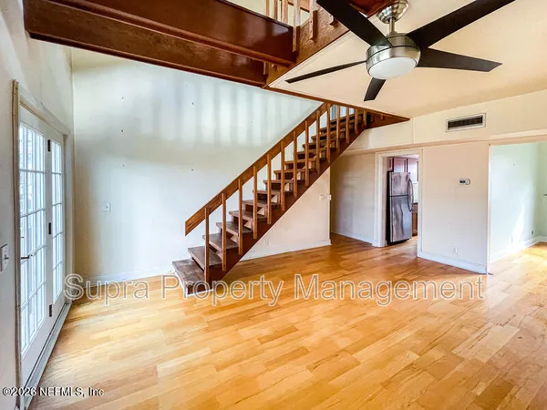 a view of an empty room with a window and wooden floor