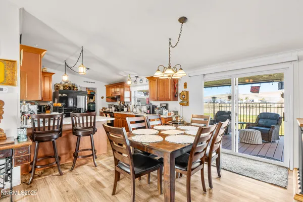 a kitchen with stainless steel appliances granite countertop a sink dishwasher a microwave oven with a dining table and chairs with wooden floor