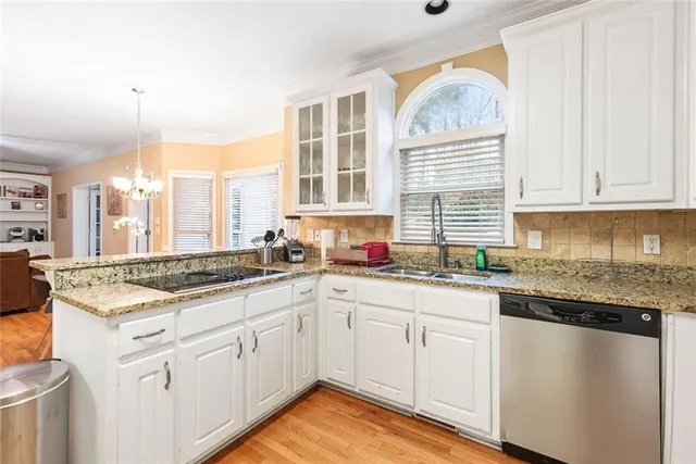 a kitchen with stainless steel appliances granite countertop a stove a sink and a granite counter tops with white cabinets