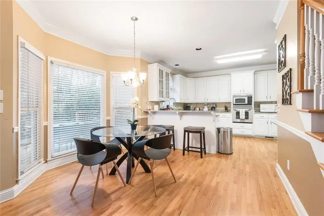 a kitchen with stainless steel appliances kitchen island granite countertop a stove a refrigerator a sink a dining table and chairs with wooden floor