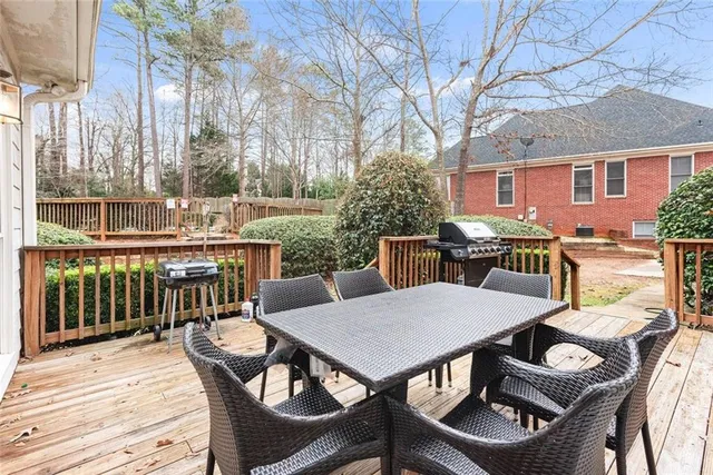 a view of a patio with table and chairs with wooden floor and fence