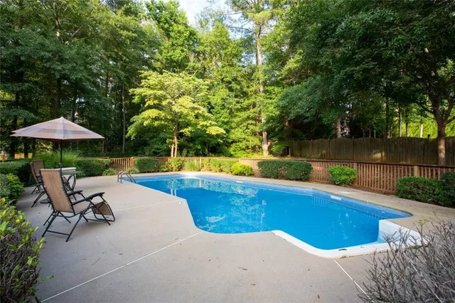 a view of a swimming pool with a table and chairs under an umbrella