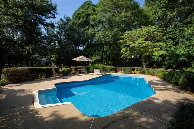 a view of a swimming pool with a patio and a yard