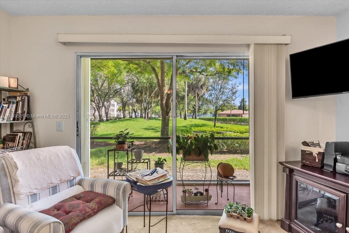 13455 Southwest 16th Court, Unit 104F Pembroke Pines, FL 33027 - Photo 8 of 53 a living room with furniture tv and a floor to ceiling window