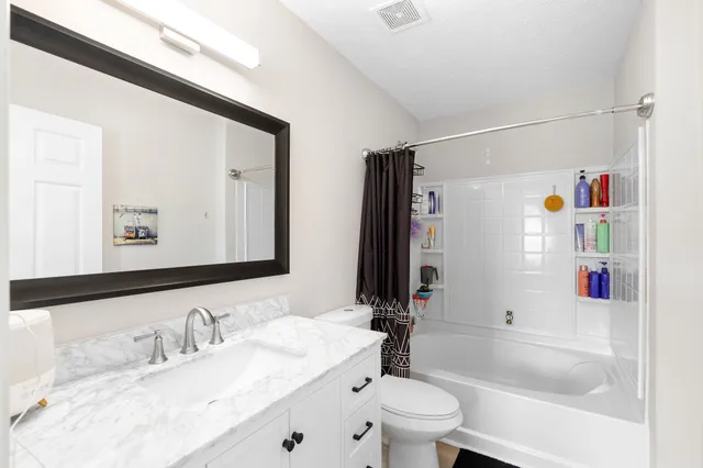 a bathroom with a granite countertop sink mirror vanity and toilet