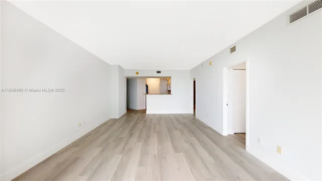 a view of a big room with wooden floor and windows