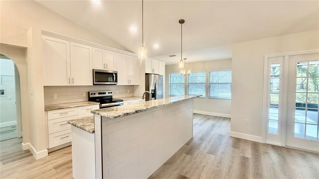 18917 Parade Road Hudson, FL 34667 - Photo 12 of 39 a kitchen with stainless steel appliances a stove top oven a sink a refrigerator a center island and wooden floor